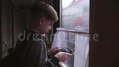 那个男孩站在火车窗口，手里拿着一块平板电脑。 坐火车<strong>旅</strong>行。 度假<strong>旅</strong>游，<strong>环游世界</strong>